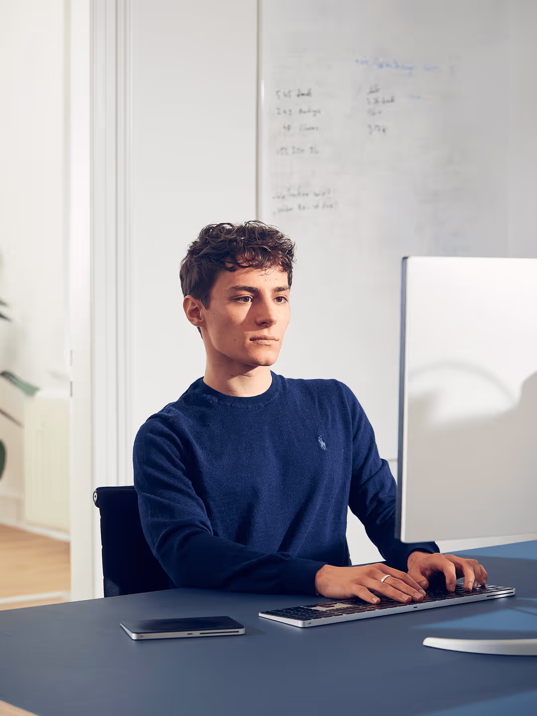 Elia arbeitet in einem modernen Altbau-Büro an einem Bildschirm. 